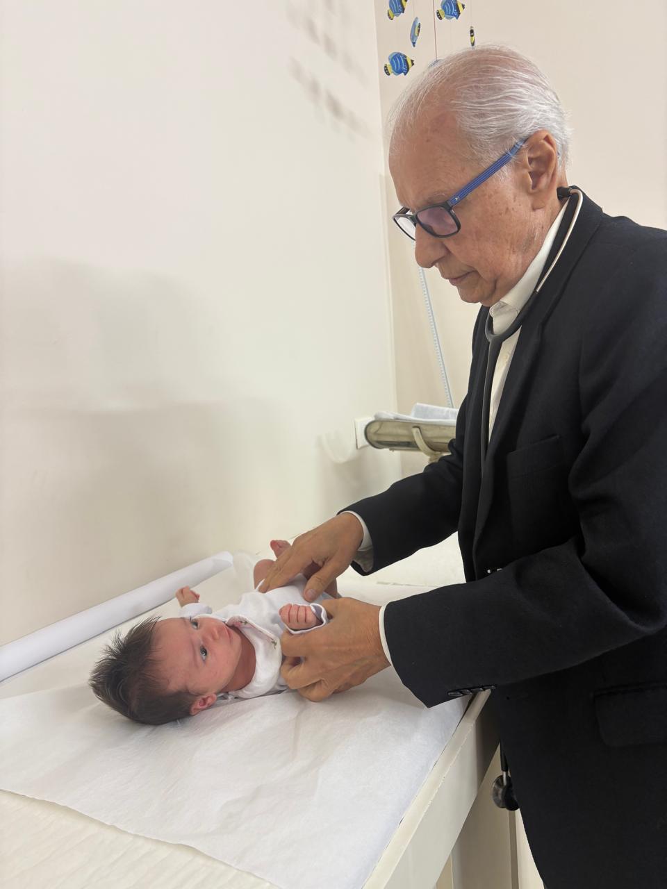 Dr. Belmiro examinando um recém-nascido em atendimento pediátrico